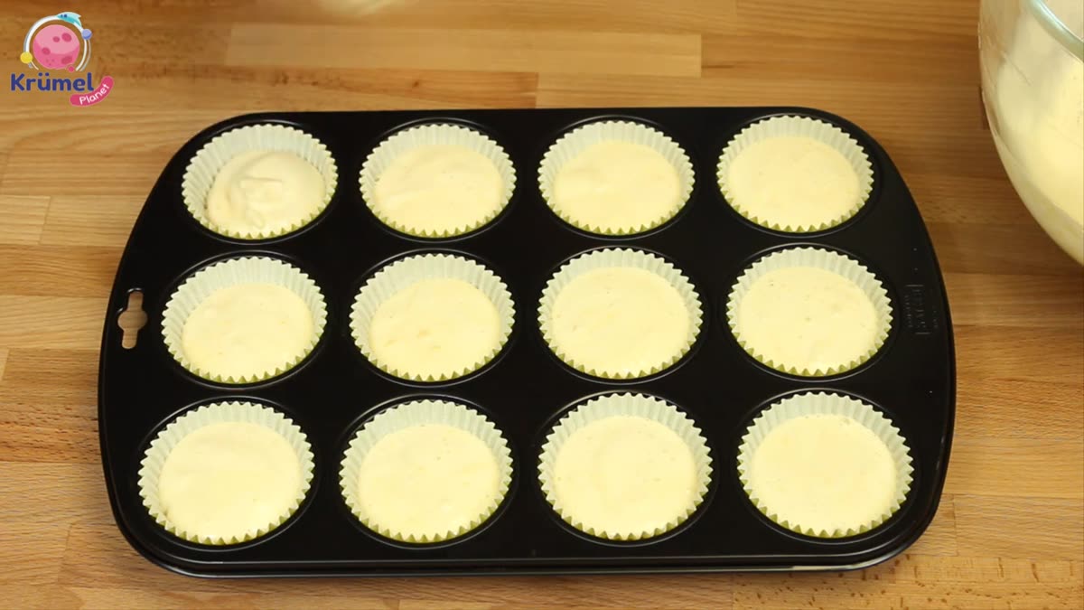 Fanta-Muffins backen: Saftig, locker und einfach gemacht - Teig in Muffinförmchen verteilen.