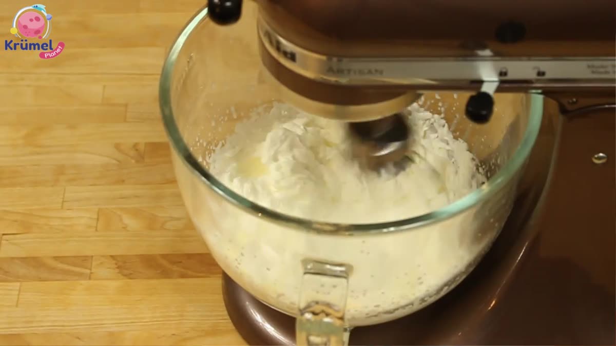 Ü-Ei Eis selber machen: Einfaches Rezept für Kinder - Die geschlagene Sahne und die gehackten Kinderriegel unter die Mascarpone-Masse heben.